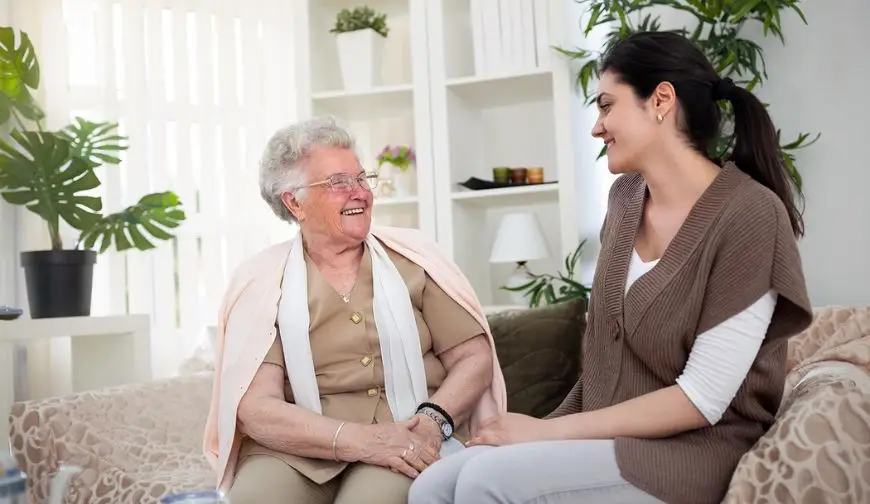 caregiver sitting talking with elderly woman at home companionship